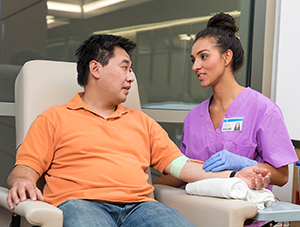 Proveedora de atención médica atendiendo a un hombre que está donando sangre.